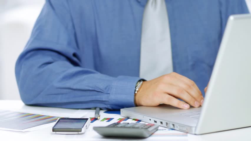 Businessman using calculator and laptop computer