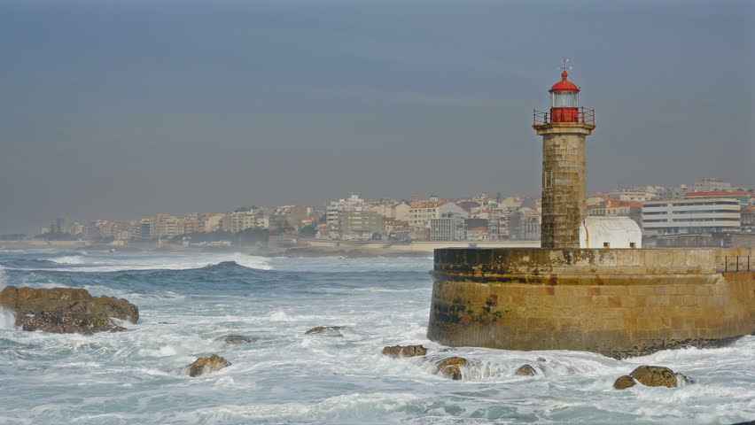 Lighthouse Felgueirasin Porto with waves and cityscape, sunny day
