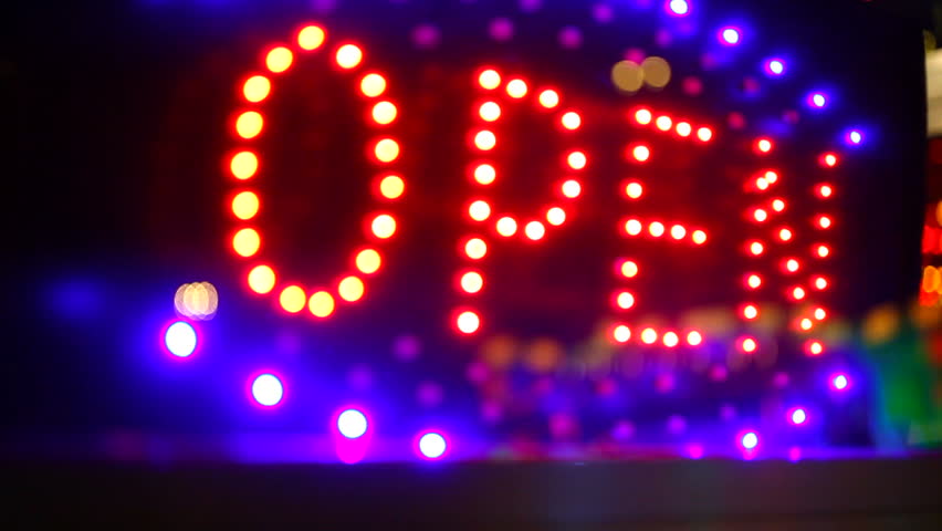Glowing open neon display sign in a window, rack focus with reflection
