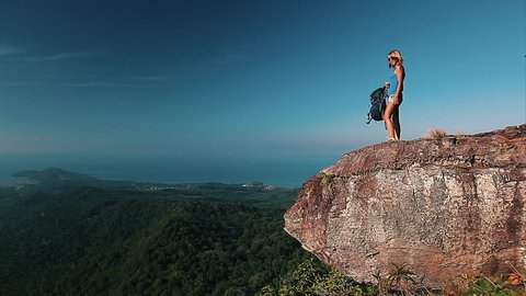 Lady with backpack standing on top of the mountain