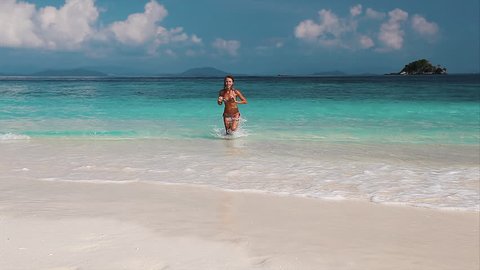 Young lady running from the tropical sea