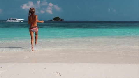 Young lady running into the tropical sea