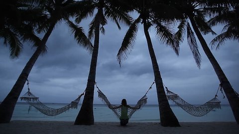 Lady relaxing in hammock among set among the palm trees