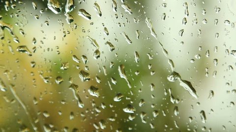Close up image of rain drops falling on a window with sound of rain and wind