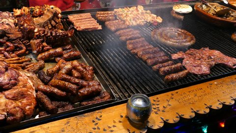 TIMISOARA, ROMANIA - DECEMBER 20, 2015: Romanian traditional sausages (mici), skewers and grill steaks on a traditional winter street fair. 4K footage.