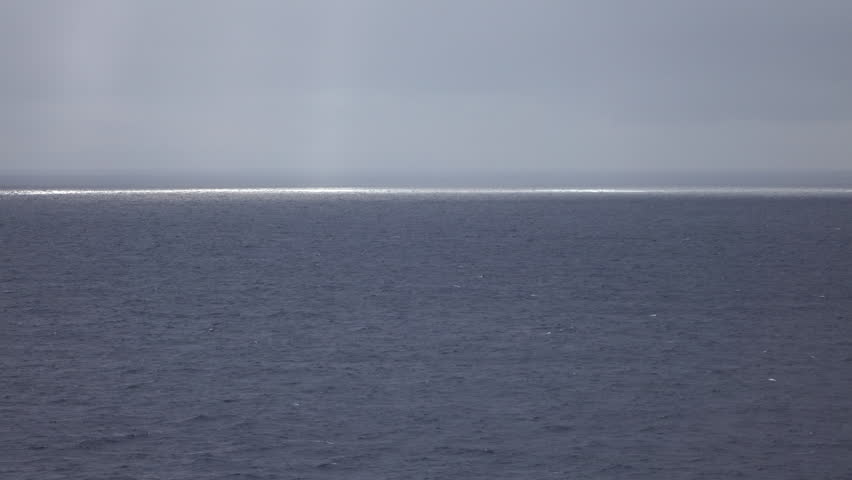 Sunshine on Caribbean Ocean rainy day 4K. Sailing of coast of Mexico on cruise ship from Galveston Texas. Sun rays shine bright on horizon during a raining afternoon. Vacation travel. Nature seascape.