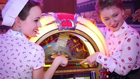 MOSCOW - JAN 18, 2015: Two girls stand near Jukebox (models with releases) at Retro Beauty Day in Beverly Hills Diner