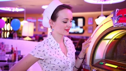 MOSCOW - JAN 18, 2015: Woman pushes button of Jukebox (model with release) at Retro Beauty Day in Beverly Hills Diner