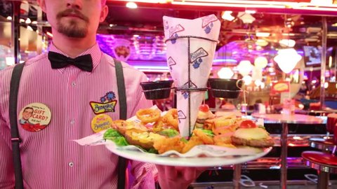 MOSCOW - JAN 18, 2015: Waiter carries dish (focus on dish) in Beverly Hills Diner - network of stylized American restaurants in Moscow