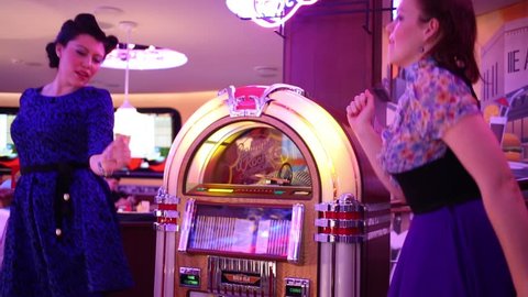 MOSCOW - JAN 18, 2015: Two women dance (models with releases) near Jukebox in Beverly Hills Diner - network of stylized American restaurants in Moscow