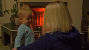 In this video, we can see that a small boy is hugging his mom in front of a fireplace in the living room. Close-up shot.