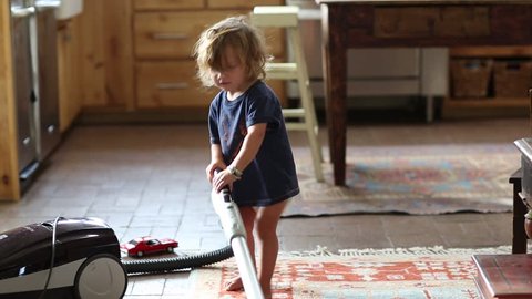 Toddler boy vacuuming at home