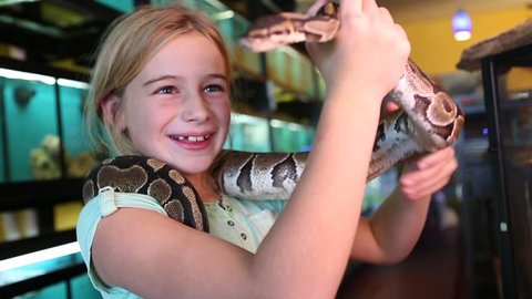 Pre-teen girl playing with snake in a pet store