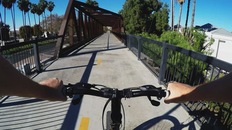 WHITTIER, CA/USA - December 14, 2015: Viewpoint shot of bicyclist on a truss bridge in Whittier California. An old rail road track has been converted into a bike path.