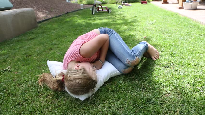 9 year old girl play with pillows on grass