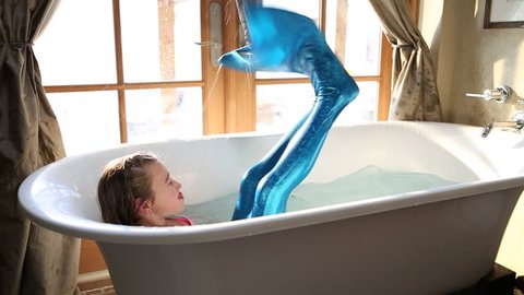 9 year old girl with fake mermaid costume in bathtub