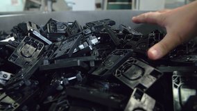 In this video, we can see many black items in a huge box. A man is grabbing a few and taking them out of the box. Close-up shot.