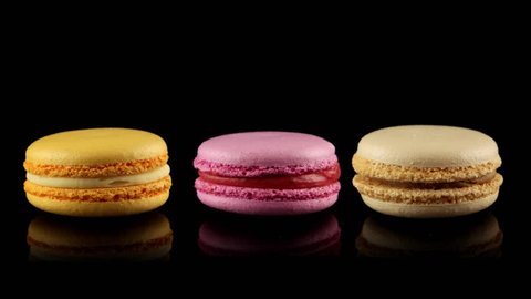 Three tasty colorful macarons rotating (horizontal view with reflection)