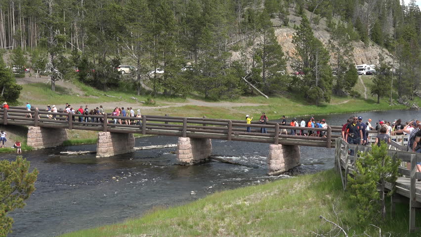 YELLOWSTONE, WYOMING - JUN 2015: Yellowstone bridge Firehole river midway geyser basin 4K. 200 by 300-foot wide Excelsior Geyser pours over 4,000 U.S. gallons per minute into the Firehole River.
