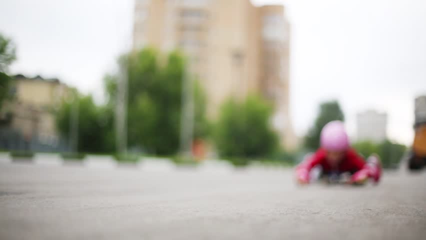 The girl lies on a skateboard and rolls toward the camera