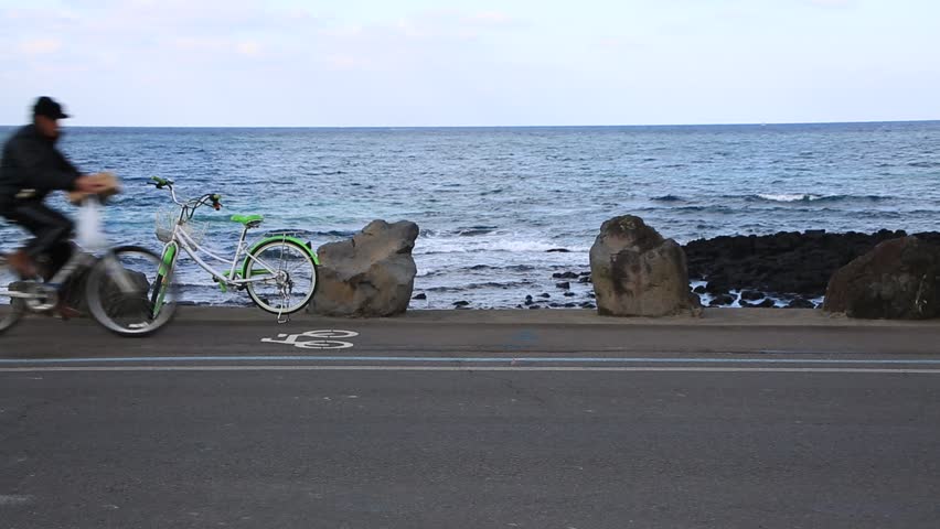 A green bicycle parked by the ocean road