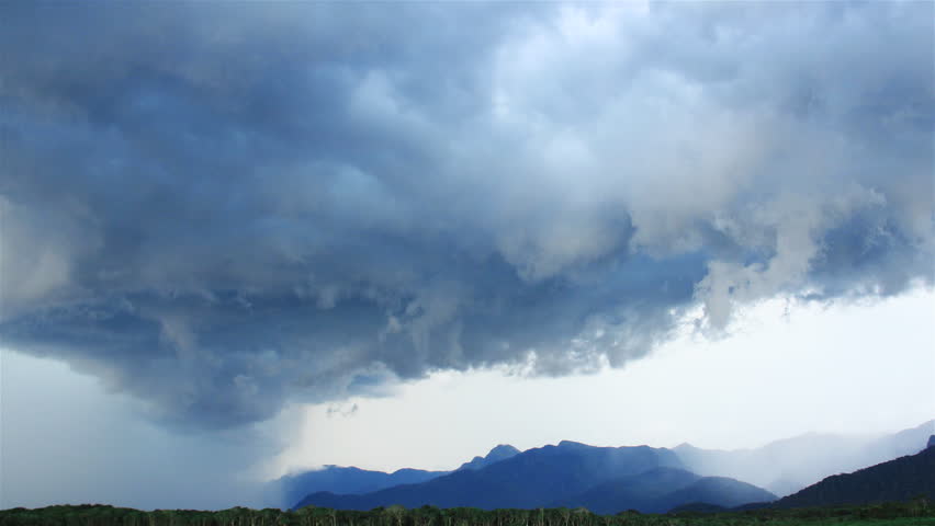 Clouds moving before a storm near some mountains.
