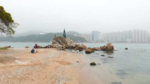 HONG KONG - FEBRUARY 22, 2015: Sea channel, sandy beach and small lighthouse on rocks, cloudy weather. Camera pan left, show beautiful landscape of Lei Yue Mun, Kwun Tong, Hong Kong