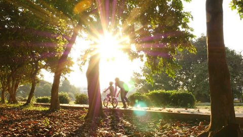 Asian daughter practice to ride a bicycle with her father, Happy family in the park, 4K Video