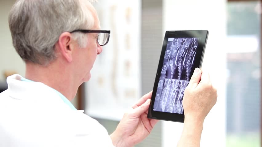 Mature medicine looking at MRI of neck on tablet PC. Royalty-Free Stock Footage #13627109