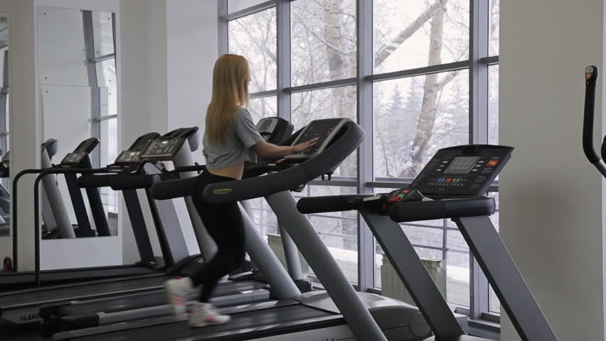 Athlete sexy woman walking, with long hair walking on a treadmill in the gym in front of panoramic windows with views of the snowy forest. She is preparing for his personal regular training. Her sexy | Shutterstock HD Video #13627469