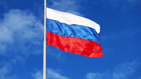 Flag of Russia on the flagpole waving in the wind against the blue sky