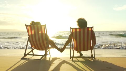Relaxing Couple on Tropical Resort Luxury Vacation. Beach Chairs in the Sunset. Slow Motion.