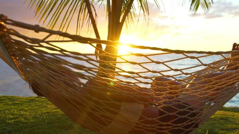 Romantic couple relaxing in tropical hammock at sunset. Summer Luxury Vacation. SLOW MOTION.