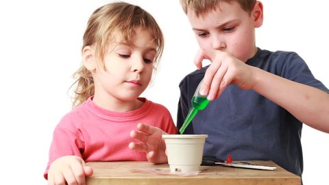 boy and little girl watered plants seeds of nutrient solution in pot with soil on table, white background