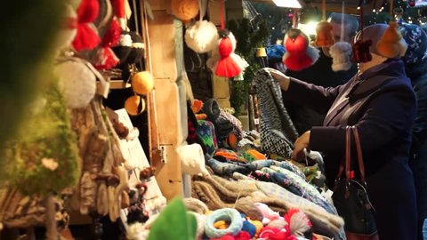 RIGA, LATVIA - DECEMBER 19, 2015: Woman buys souvenirs at  Christmas Fair in old town at evening on December 15, 2015 in Riga, Latvia