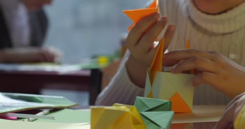 KIEV/UKRAINE - JUL 14 2015: Paper origami. Three kids make origami from colored paper. Origami contest. Making of kusudama. Assemble of modular origami, unit origami. Close view. Indoors. Kiev,