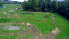 In this video, we can see that a motorcycle is overcoming small hills on the track. There are many dirt tracks around, too. Wide-angle shot.