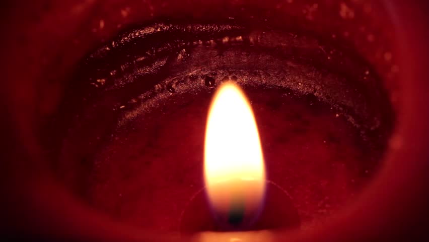 A flame burns on a red candle