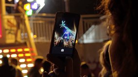 Hand with smartphone taking video in amusement park