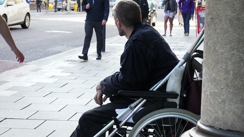 homeless bagging in the street: young disable on wheel chair