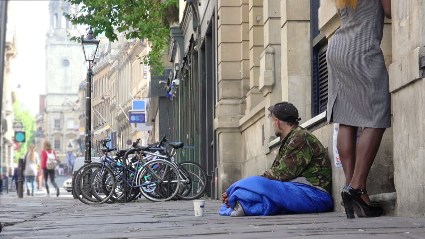 young outcast homeless begging in the street among the passers