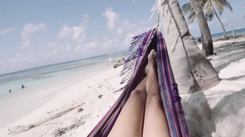 Hispanic woman relaxing in hammock on caribbean beach at San Blas islands, Panama