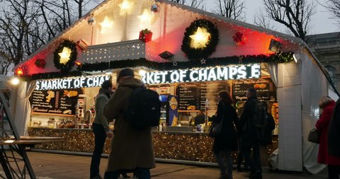 PARIS, FRANCE - CIRCA 2015: Happy people enjoying Christmas Market with diverse chalet Christmas stall selling food and mulled wine on Champs-Elysees with friends buying gluhwein mulled wine