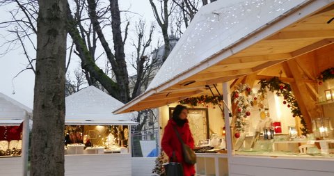 PARIS, FRANCE - CIRCA 2015: Zoom out from woman and child eating sweet food under miniature Eiffel Tower at Christmas Market with as diverse chalet Christmas stall selling food and mulled wine 