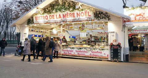 PARIS, FRANCE - CIRCA 2015: People enjoying Christmas Market with Bistro de la mere Noel market stall selling diverse food and mulled wine on Champs-Elysees with friends buying gluhwein mulled wine