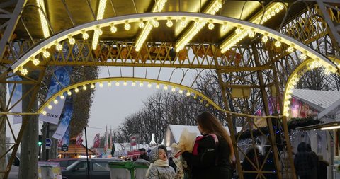 PARIS, FRANCE - CIRCA 2015: Woman and child eating sweet food under miniature Eiffel Tower at Christmas Market with as diverse chalet Christmas stall selling food and mulled wine