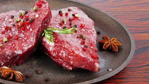 fresh raw beef fillet mignon on old retro style cast iron pan over retro wood table as background 1920x1080 intro motion slow hidef hd