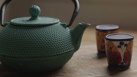 a green traditional tea chest with two colorful cups, and a human hand take the lid of the tea chest and comes out the steam, after he close it / a green traditional tea chest with two colorful cups Stockvideo