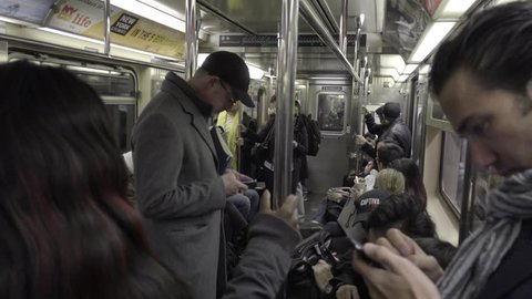 NEW YORK - DEC 7, 2015: close-up of man on smartphone standing riding crowded subway train interior in 4K NYC. MTA serves the city's 5 boroughs with public transportation.