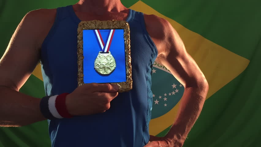 Athlete choosing gold medals on his tablet standing against Brazilian flag